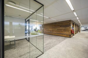 Modern office interior at Jacob Bontiusplaats with glass meeting rooms, wood-paneled walls, and neutral flooring.
